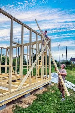 Construction of timber frame house on foundation of concrete blocks, two wo.. Stock Photos