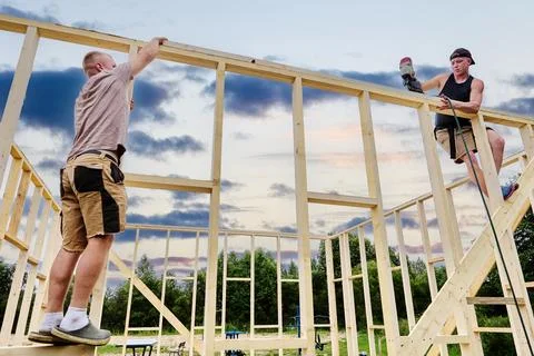 Construction of timber frame house on foundation of concrete blocks, two wo.. Stock Photos