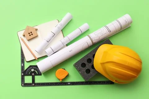Construction tools and blueprints with yellow safety helmet on green backgrou Stock Photos