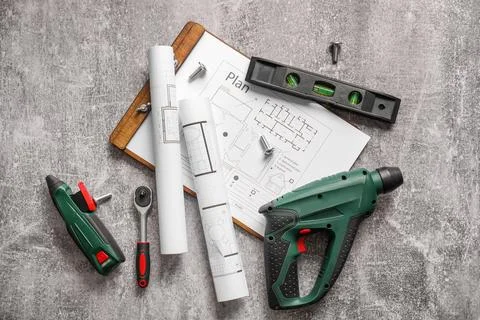 Construction tools and clipboard with house plans on grey grunge background Stock Photos