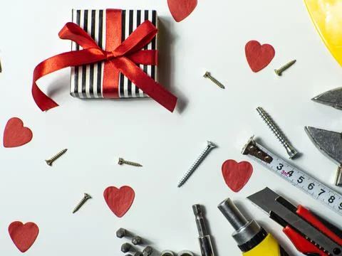 Construction tools and gift on white background with small red hearts Stock Photos