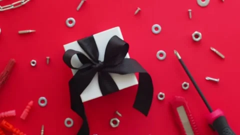 Construction tools and wrapped gift on red background Stock Footage 246616694