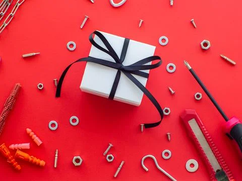 Construction tools and wrapped gift on red background Stock Photos