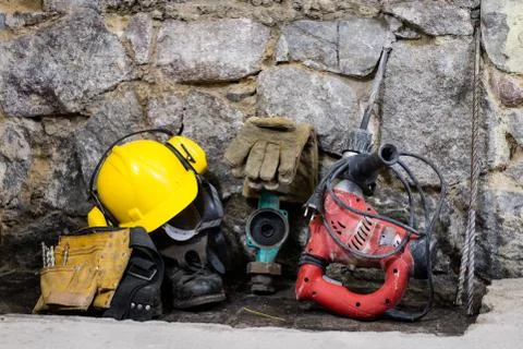 Construction tools for building a house on a stone wall. Hammer, helmet, and  Stock Photos