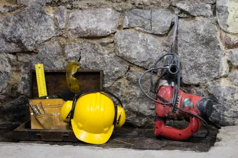 Construction tools for building a house on a stone wall. Hammer, helmet, and  Stock Photos