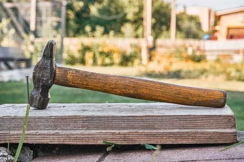 Construction tools for carpenter hammer and nail sticking out of the board Stock Photos