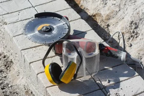 Construction tools, protective goggles, ear muffs, and a circular saw blade l Stock Photos