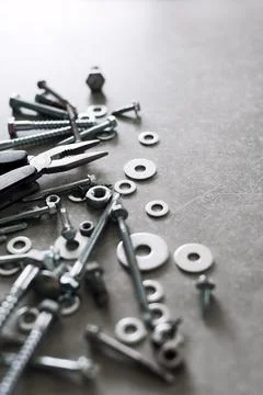 Construction tools. The screws, nuts and bolts with pliers on concrete backgr Stock Photos