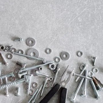 Construction tools. The screws, nuts and bolts with pliers on concrete backgr Stock Photos