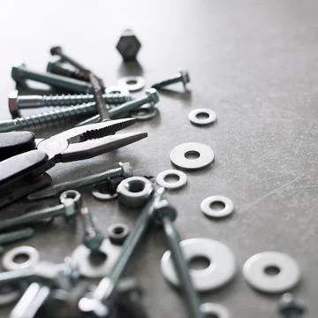 Construction tools. The screws, nuts and bolts with pliers on concrete backgr Stock Photos