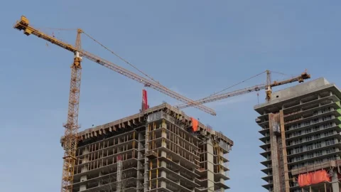 Construction. Tower crane carrying a load between two new high-rises. 動画素材 147963271