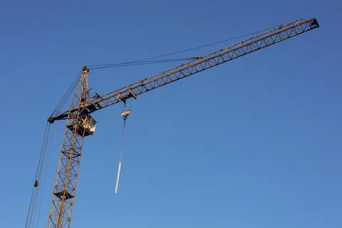 Construction tower crane with long boom on bright blue sky background. Stock Photos