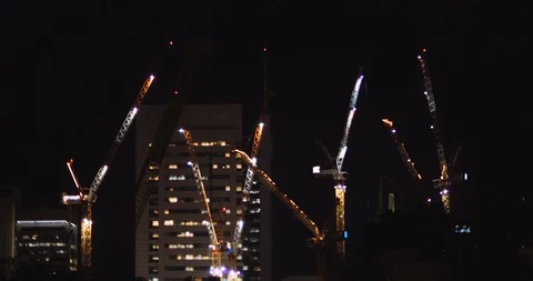 Construction tower cranes with skyscrapers at the background at night. BMPCC 4K Stock Footage 125847906
