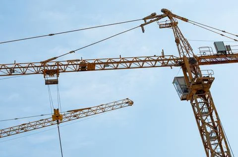 Construction tower cranes working under a clear blue sky Stock Photos