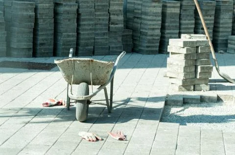 Construction trolley with workers gloves and pavement stone Stock Photos