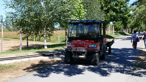 A construction vehicle carrying weeding tools drives through the zoo area Stock Footage 269654929