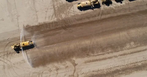 Construction Vehicle Drives Fast Sprays Water Over Dirt Field Aerial Footage Stock Footage 97865623
