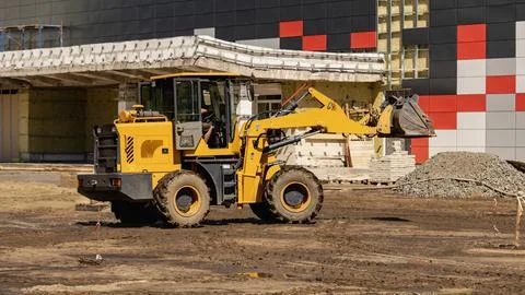 A construction vehicle is working on a site where workers are arranging mat.. Stock Photos