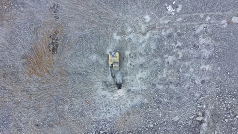 Construction vehicle works on a rocky surface to clear land for a new project in Stock Footage 337913642