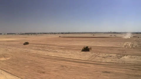 Construction vehicles crossing graded sand with distant dust 库存影片 346429605