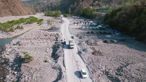 Construction vehicles moving through dry river valley aerial view 库存影片 334116835