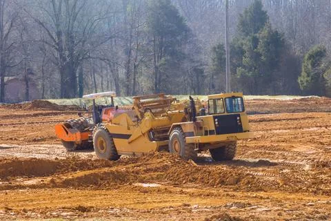 Construction vehicles working on site with dirt trees Stock Photos