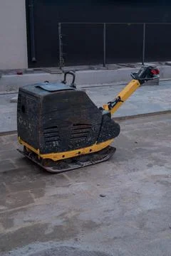 A construction vibratory plate compactor standing on the ground at a building Stock Photos
