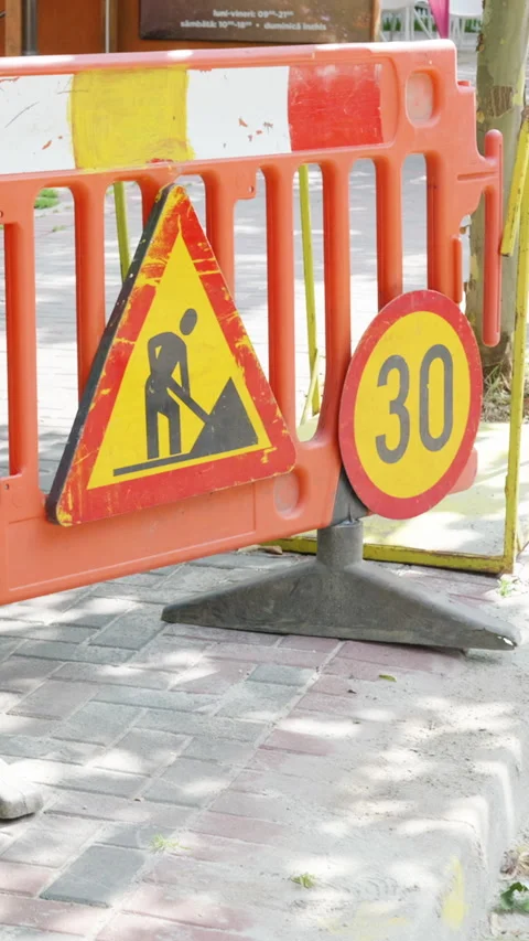 Construction warning signs displayed on an orange barrier indicating road work Stock Footage 341438203