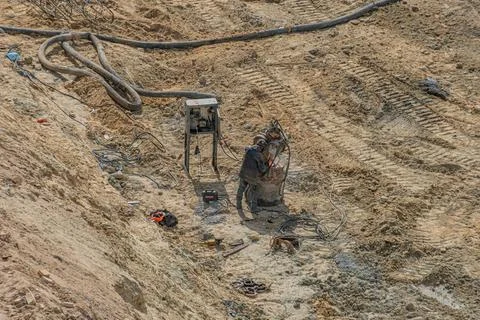 Construction Welding Scene with Worker and Equipment in Sandy Terrain 写真素材