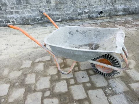 Construction Wheelbarrow on Paved Walkway at Work Site Stock Photos