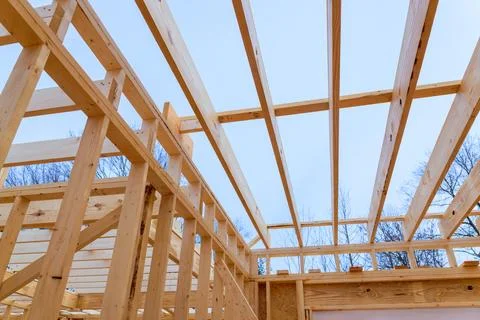 Construction of a wooden frame structure under a clear sky with exposed beams Stock Photos