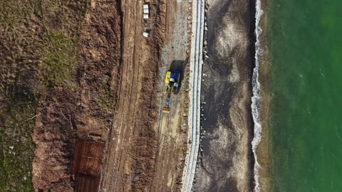 Construction work along the coastline where machinery is moving earth and Stock Footage 336542182