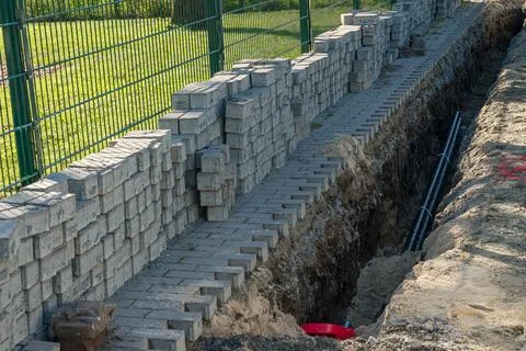 Construction work on a brick wall expanding alongside a trench for utilities Stock Photos