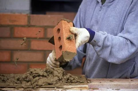 Construction work. Bricklayer applies mortar while constructing brick wall, 스톡 사진