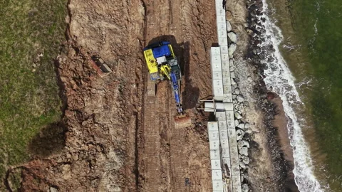 Construction work on a coastal area with heavy machinery moving earth near the Stock Footage 340154145