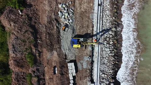 Construction work on a coastal site including heavy machinery and concrete Stock Footage 339480676