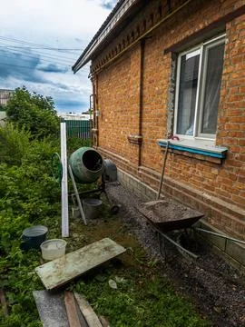 Construction work with concrete around a brick house, concrete mixer and Stock Photos