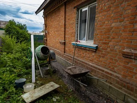 Construction work with concrete around a brick house, concrete mixer and Stock Photos