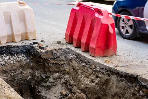 Construction work creates road hazard with open trench and barriers Stock Photos
