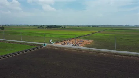 Construction work going on near green paddy fields, aerial point of Stock Footage 247701045