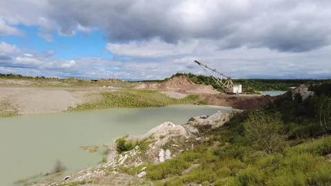Construction work at a gravel pit near a water body with a cloudy sky overhead 動画素材 340448224