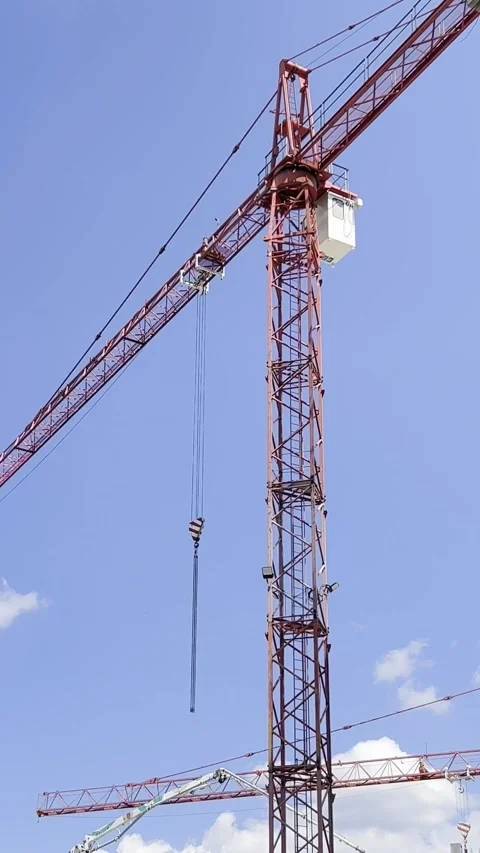 Construction work with a high-rise crane on a blue sky background. Construction Video stock 250384843