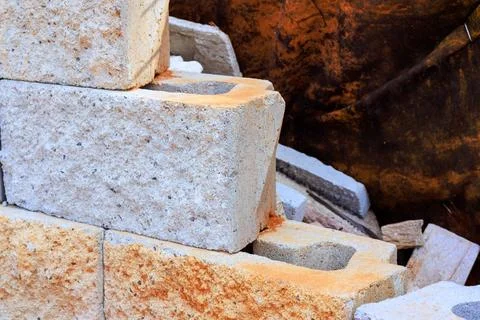 Construction work involves stone blocks stacked in building site with dirt Stock Photos