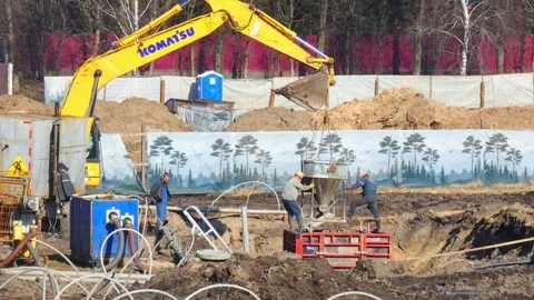 Construction work in a large excavation site with heavy machinery and workers in Stock Footage 337532612