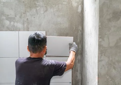 Construction work laying tile on the wall Stock Photos