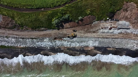Construction work is ongoing along the coastline as heavy machinery prepares the Stock Footage 341374412