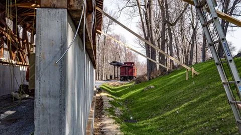 Construction Work is Ongoing Near a Red Train Car in a Wooded Area During S.. Stock Photos