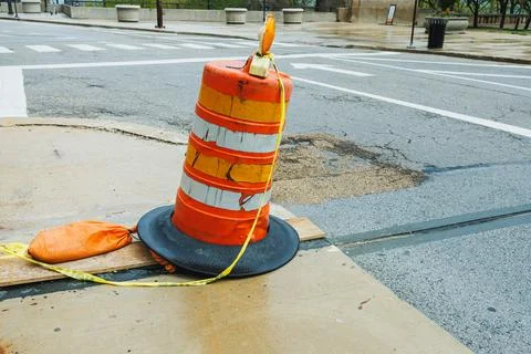 Construction work is in progress on a city street with a traffic cone and a.. 写真素材