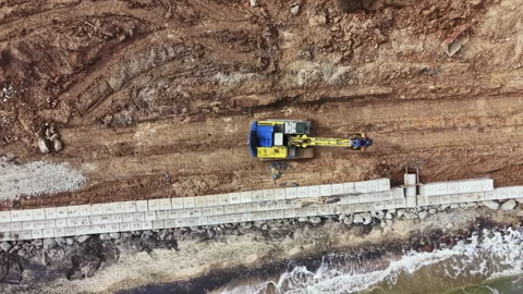 Construction work is in progress near the shoreline with heavy machinery moving Stock Footage 336565162