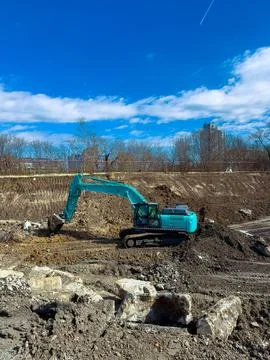 Construction work is in progress at a site with a blue excavator digging ea.. Stock Photos